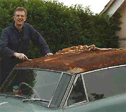 George busily scrapes off the vinyl roof