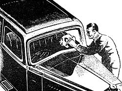A garage worked cleaning a pre-war car's windscreen