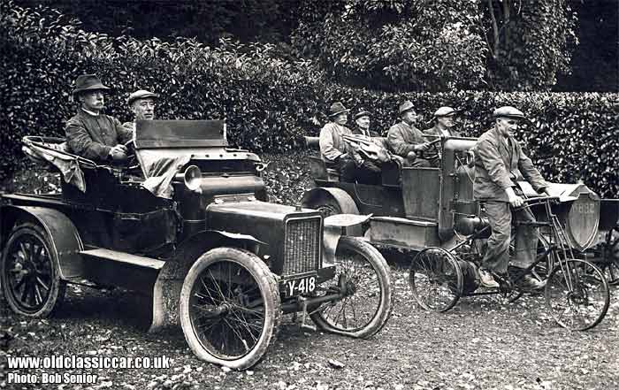 A powered tricycle and two veteran cars