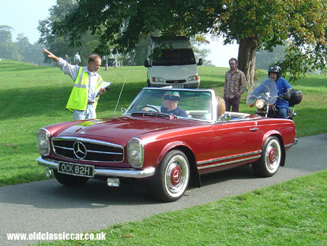 A Mercedes SL glides up to the gate at a classics show.