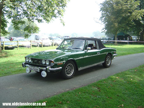A Mk2 Triumph Stag sporting a large pair of Cibie Oscars arrives at a show.