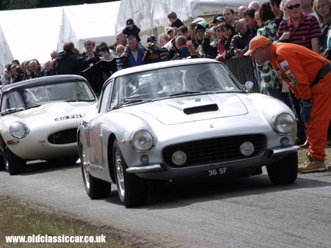 V12 Ferrari leads straight-six Jaguar up to the startline at Cholmondeley.