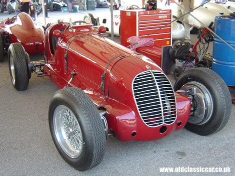A Maserati GP car photographed within the paddock area at a Goodwood Revival meeting.